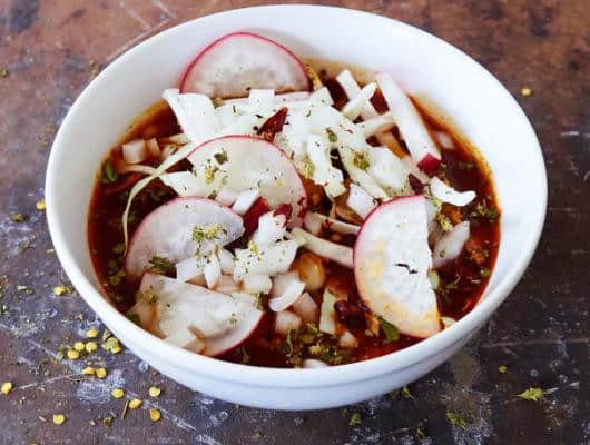 Pork Pozole and hominy in a mildly spicy chile broth garnished with shredded cabbage